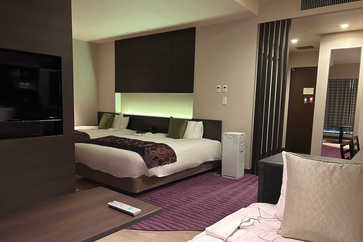 A hotel room with a bed, a desk, a TV, and a bedside table.