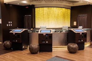 A reception area with three self-service kiosks, a curved wall with a golden curtain, and a wooden floor. - Hotel Keihan Kyoto GRANDE (Kyoto)