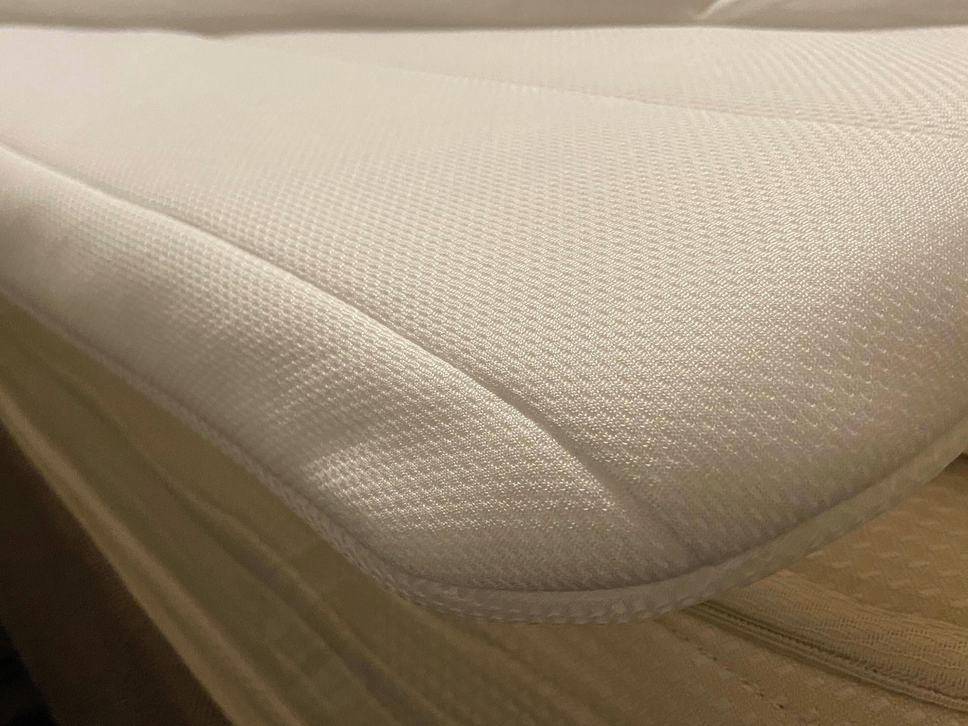 Un gros plan d’un tissu blanc à texture particulière, probablement un matelas ou un coussin.