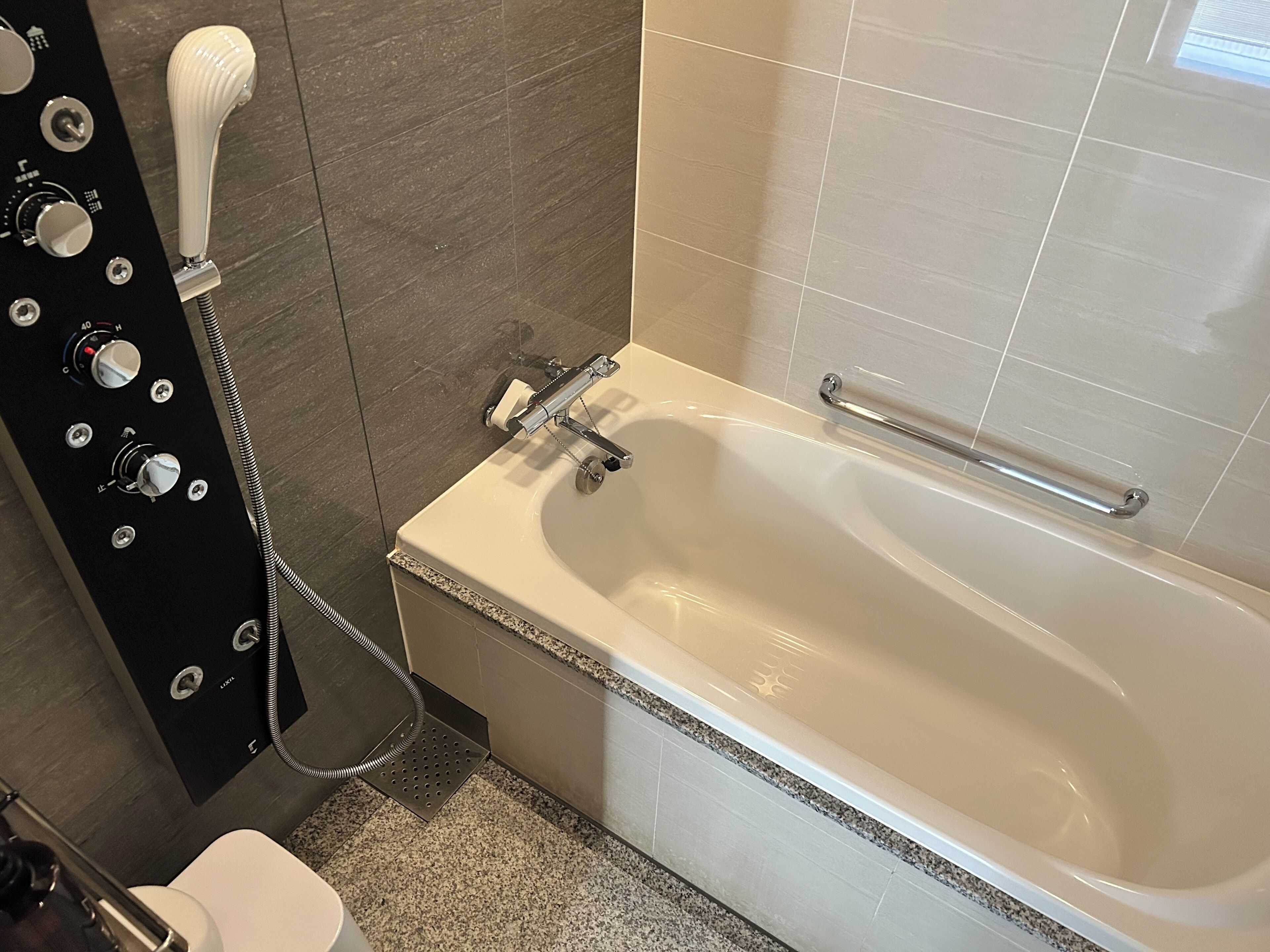 A modern bathroom with a bathtub, a hand shower, and a toilet.