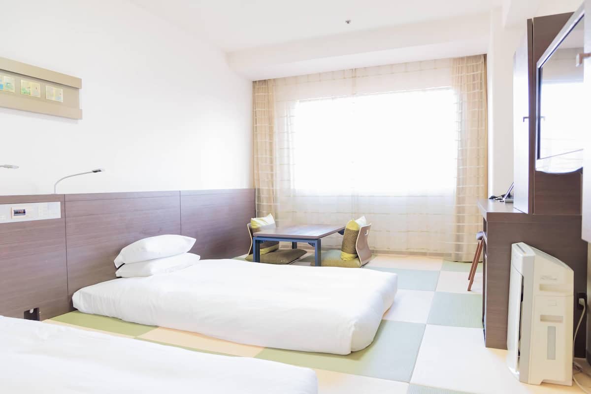 A hotel room with two beds, a small table, and a TV.