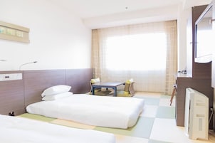 A hotel room with two beds, a small table, and a TV.
