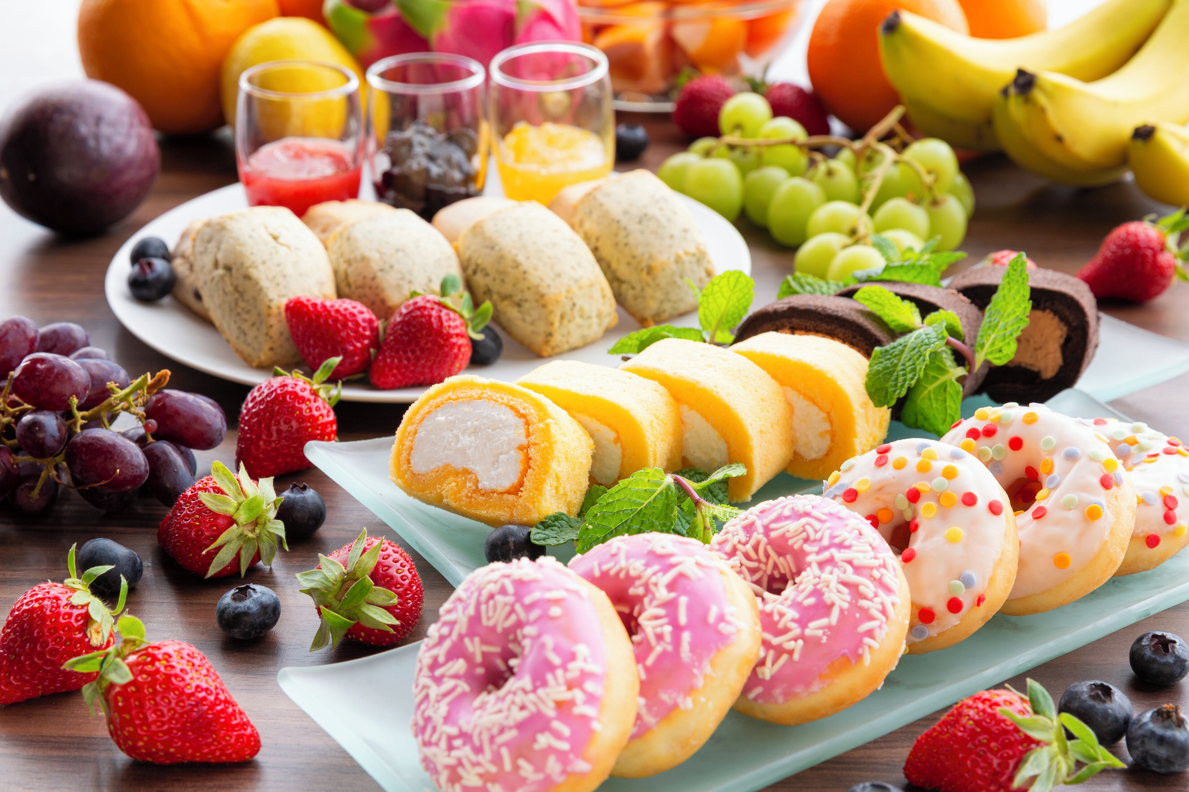 A variety of pastries, fruits, and beverages on a table.
