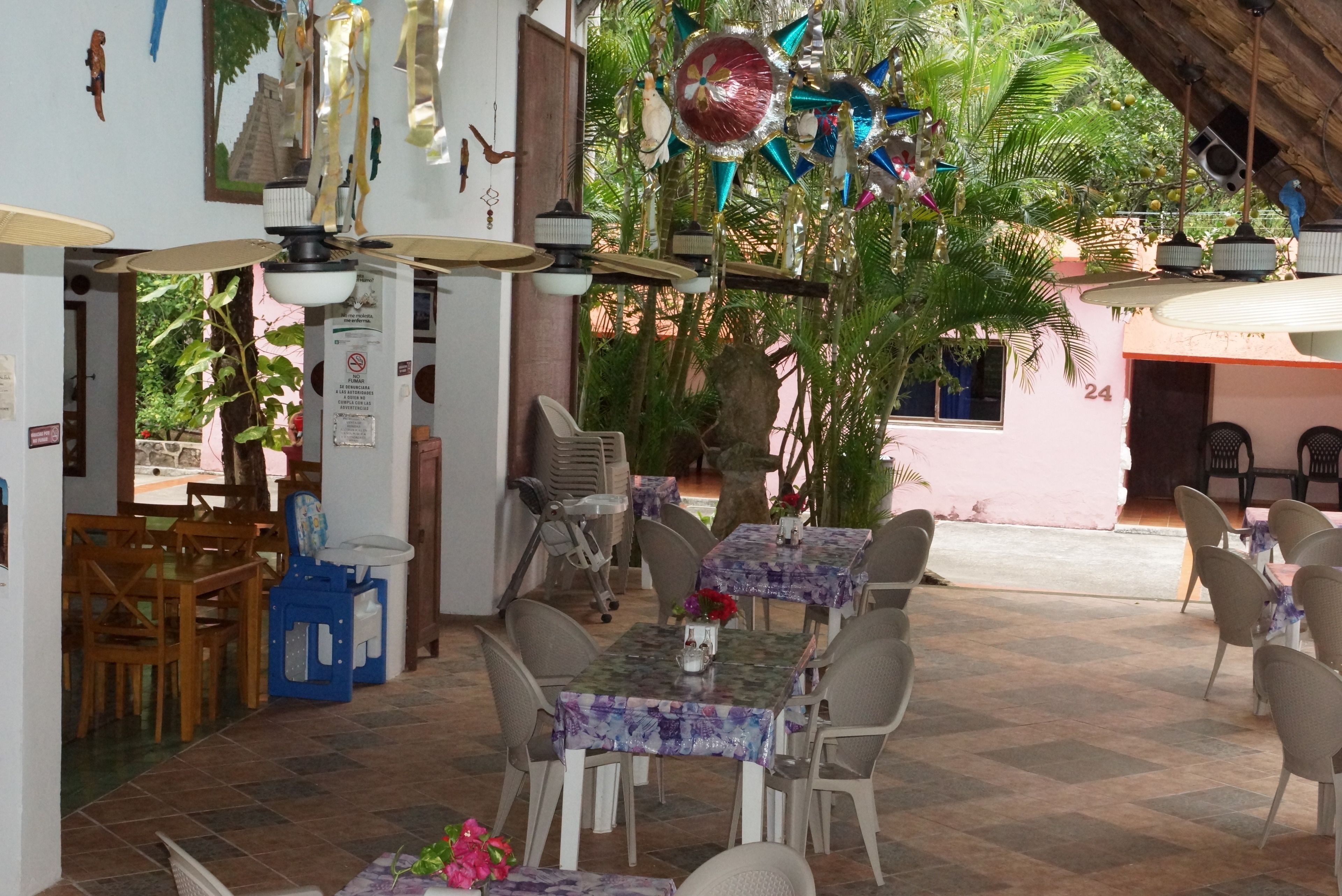 An outdoor dining area with tables and chairs, surrounded by greenery and decorative elements.