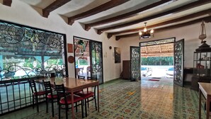 Comedor con mesa y sillas de madera, una puerta de metal decorativa y vistas al exterior.