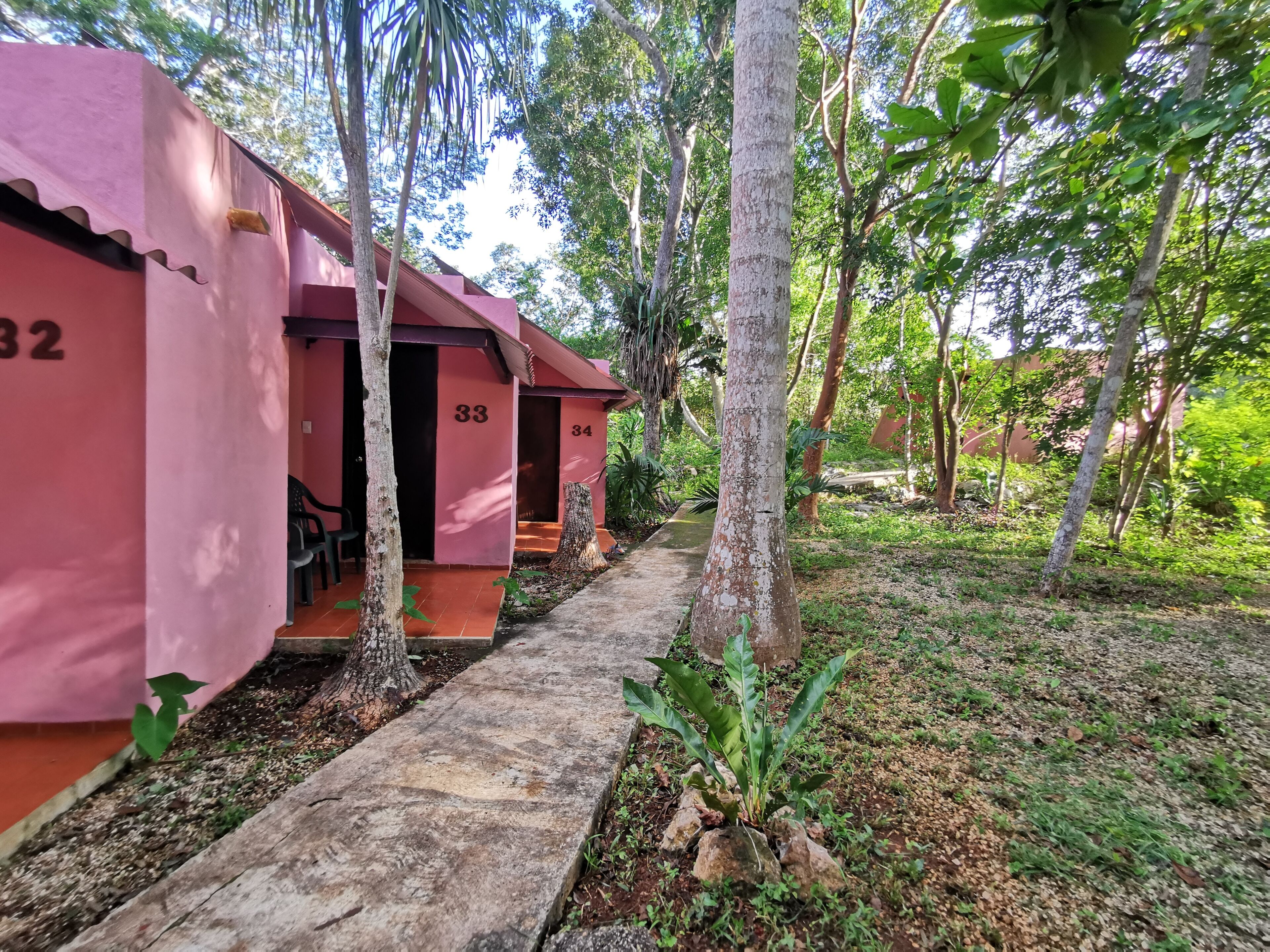 Una hilera de edificios rosados, los números 32, 33 y 34, con un sendero que atraviesa un jardín.