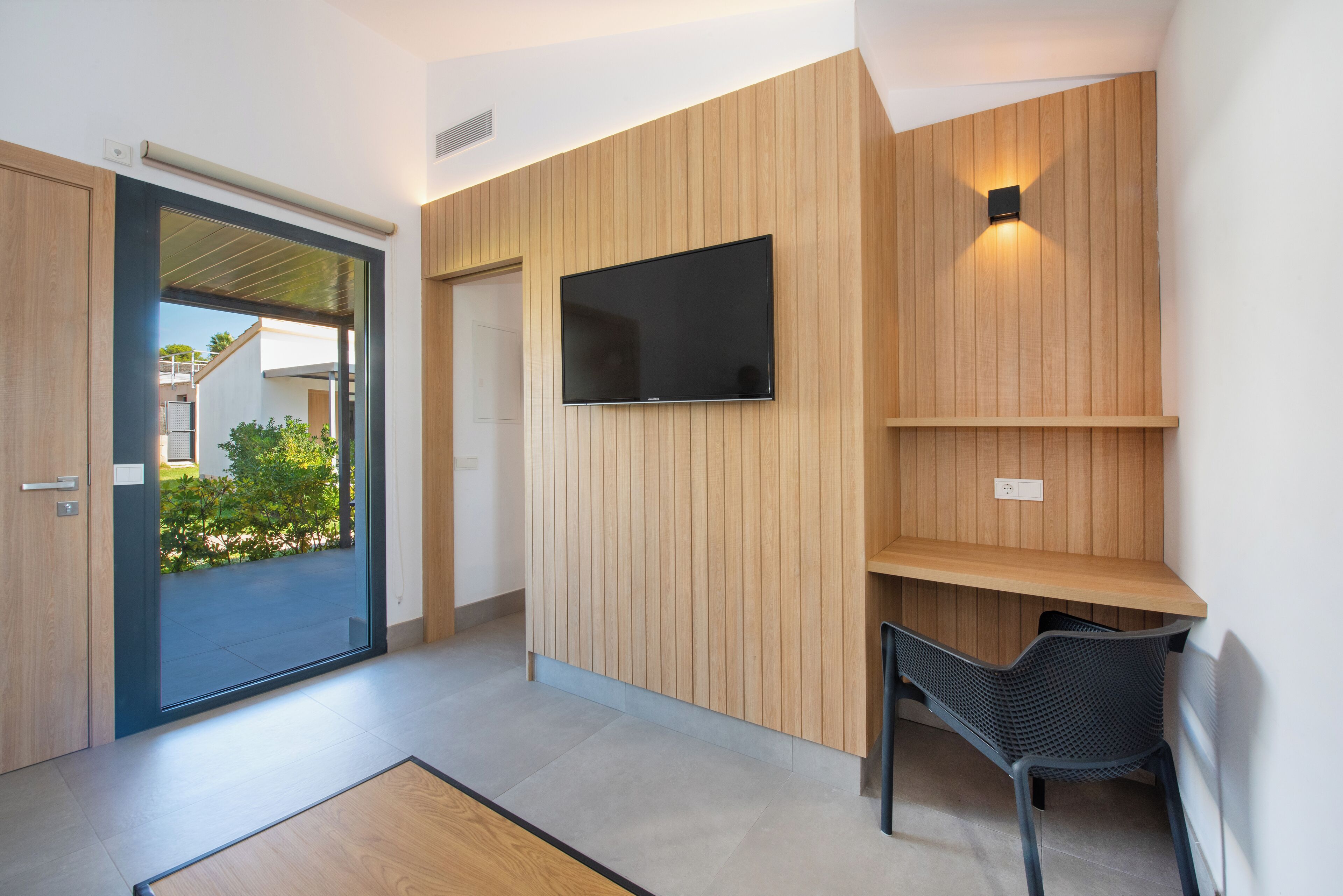 A modern interior with a wooden wall panel, a mounted TV, and a seating area.