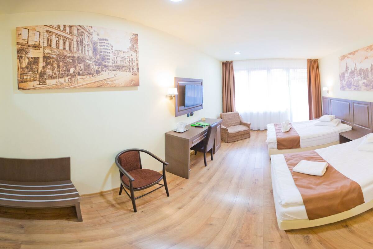 Ein Hotelzimmer mit Bett, Schreibtisch, Stuhl und Fernseher.