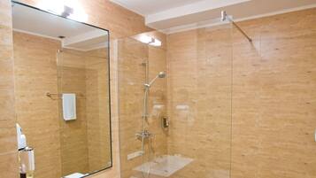 Un baño moderno con cabina de ducha de vidrio, un espejo grande y un lavabo blanco.