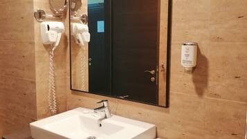 Un baño con lavamanos blanco, un espejo, un secador de pelo y una toalla.