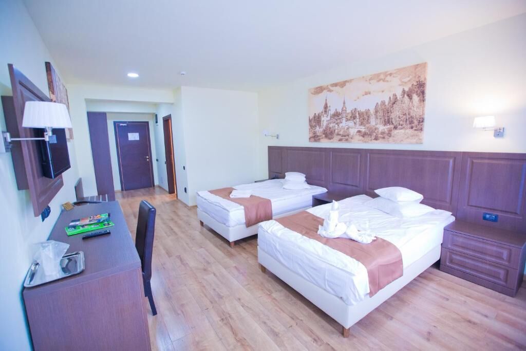 Une chambre d’hôtel avec deux lits, un bureau avec une chaise, une télévision et un tableau au mur.