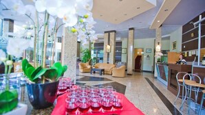 A hotel lobby with a reception desk, seating area, and potted plants. - Hotel Piemonte (Predeal)