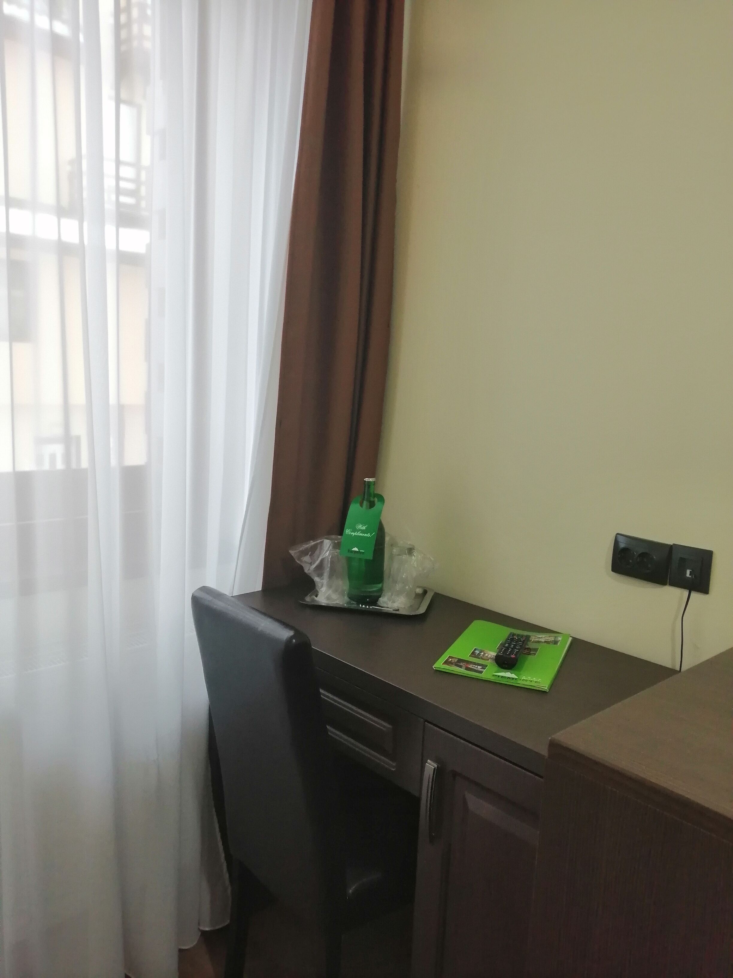 A small office space with a desk, chair, and a window with curtains.