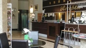 A hotel lobby with a reception desk, a coffee bar, and a seating area with chairs and a table. - Hotel Piemonte (Predeal)