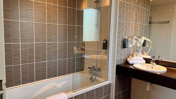 Een moderne badkamer met een douche met glazen wand, een wastafel met twee wasbakken en een handdoekrek.
