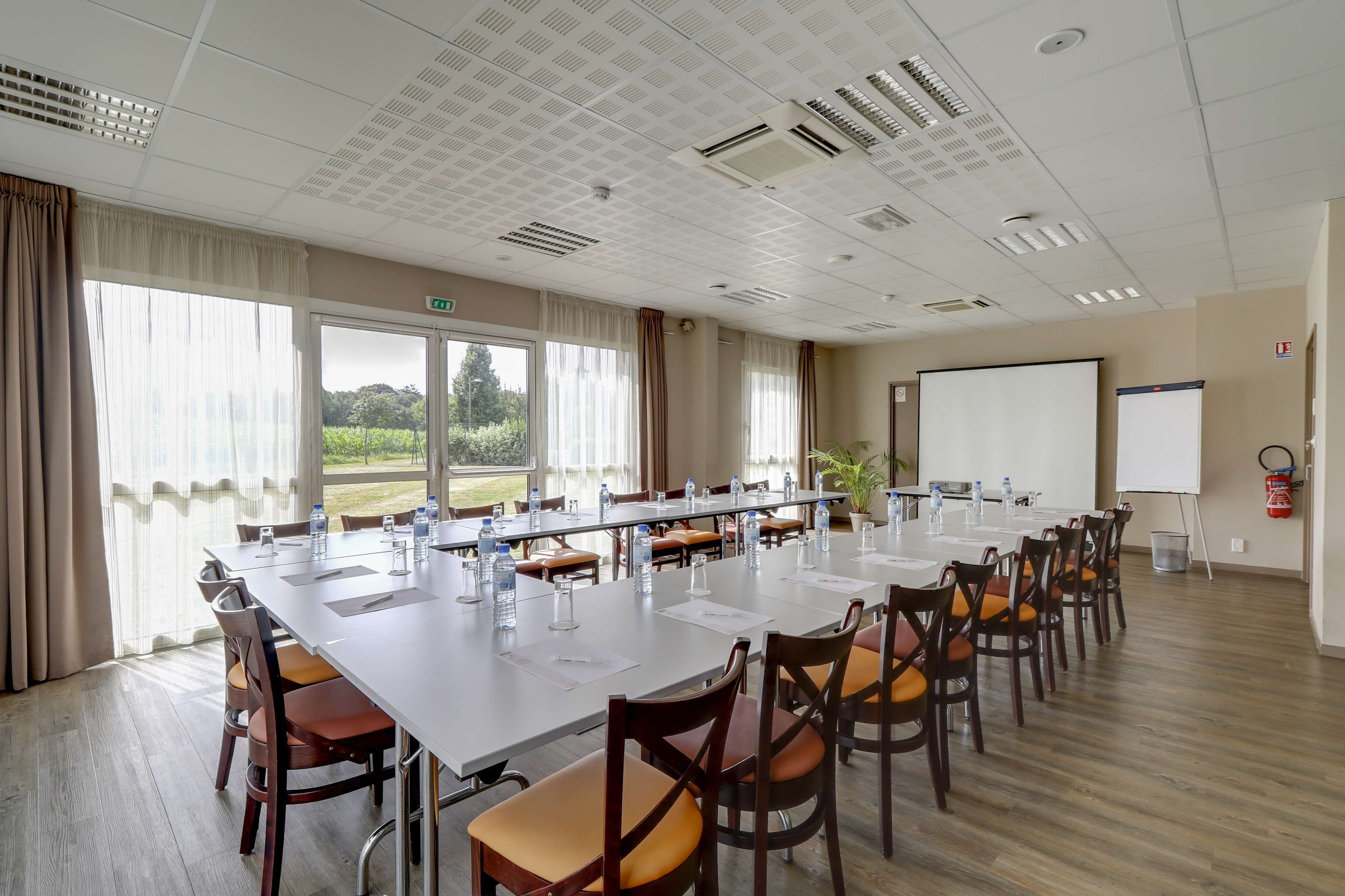A conference room with a long table, chairs, a projector screen, and a whiteboard.