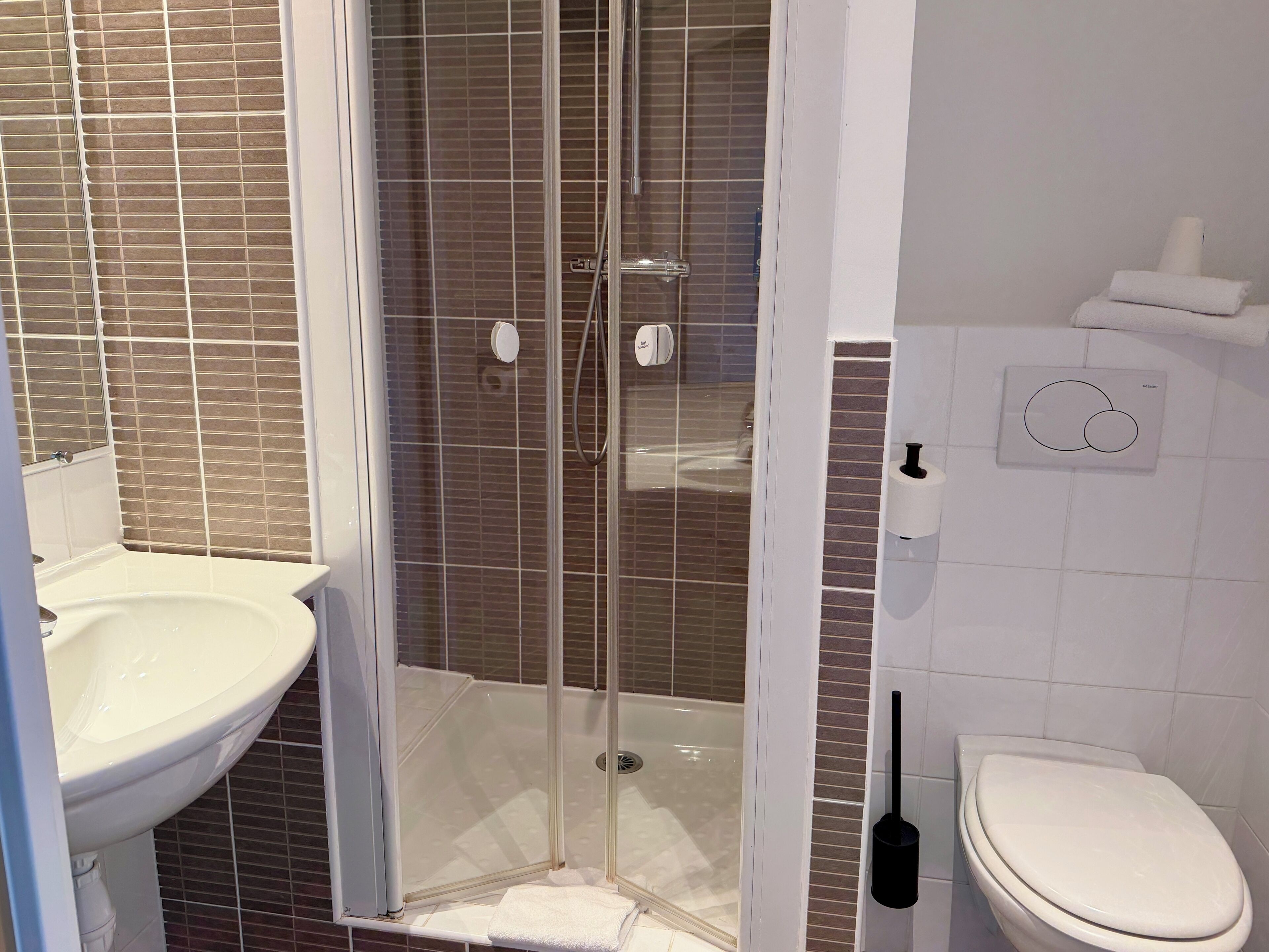 A bathroom with a glass-enclosed shower, a sink, and a toilet.