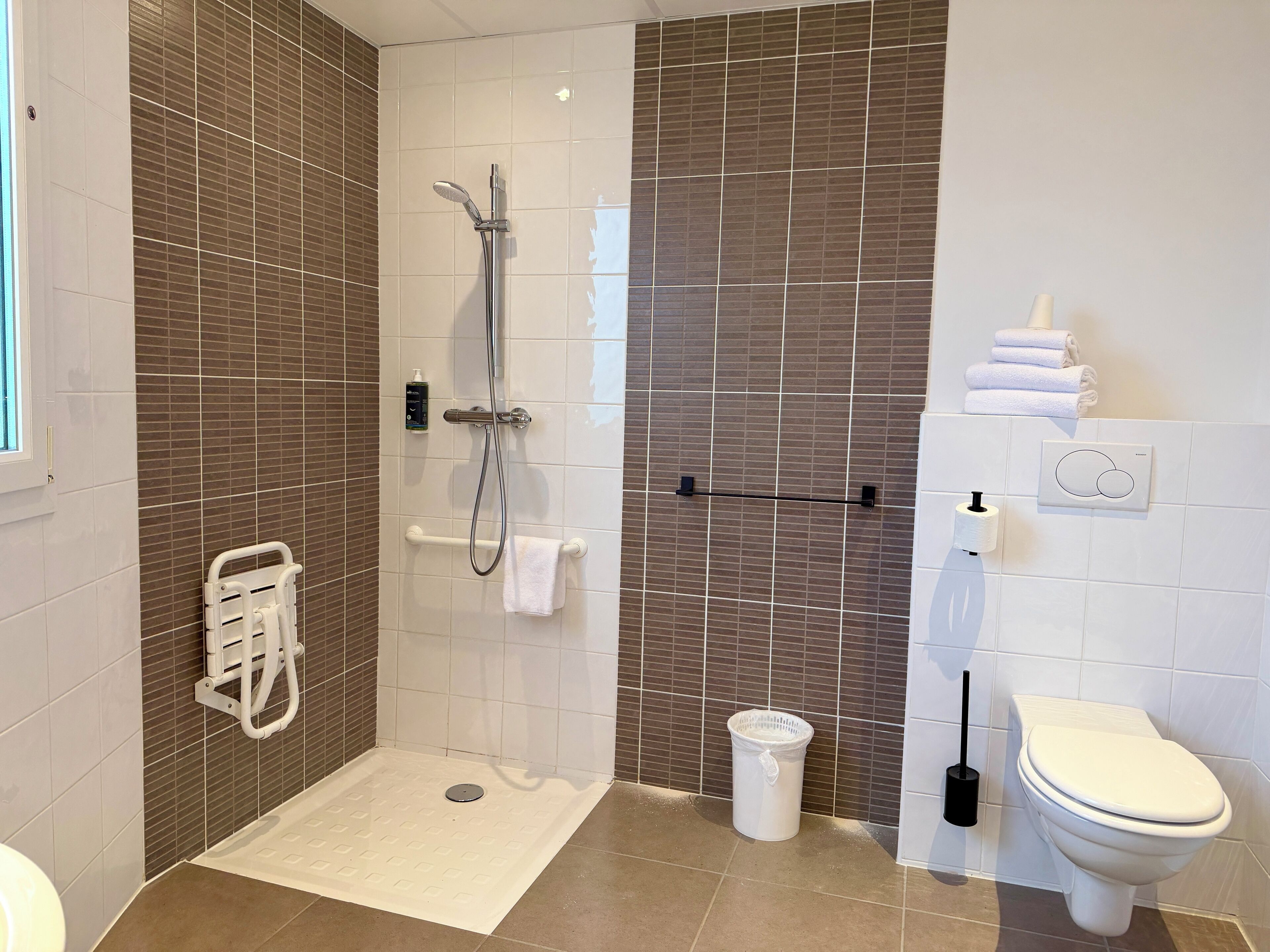 A modern bathroom with a shower, toilet, and hand dryer.