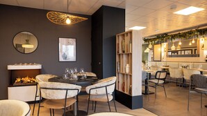 Un espace repas moderne avec une table ronde centrale, des chaises rembourrées, une bibliothèque et une cheminée.