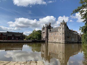 Een historisch gebouw van steen met meerdere torens en een gracht.