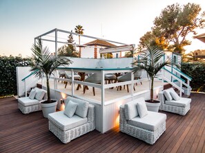 A covered outdoor seating area with wicker furniture and a glass railing.