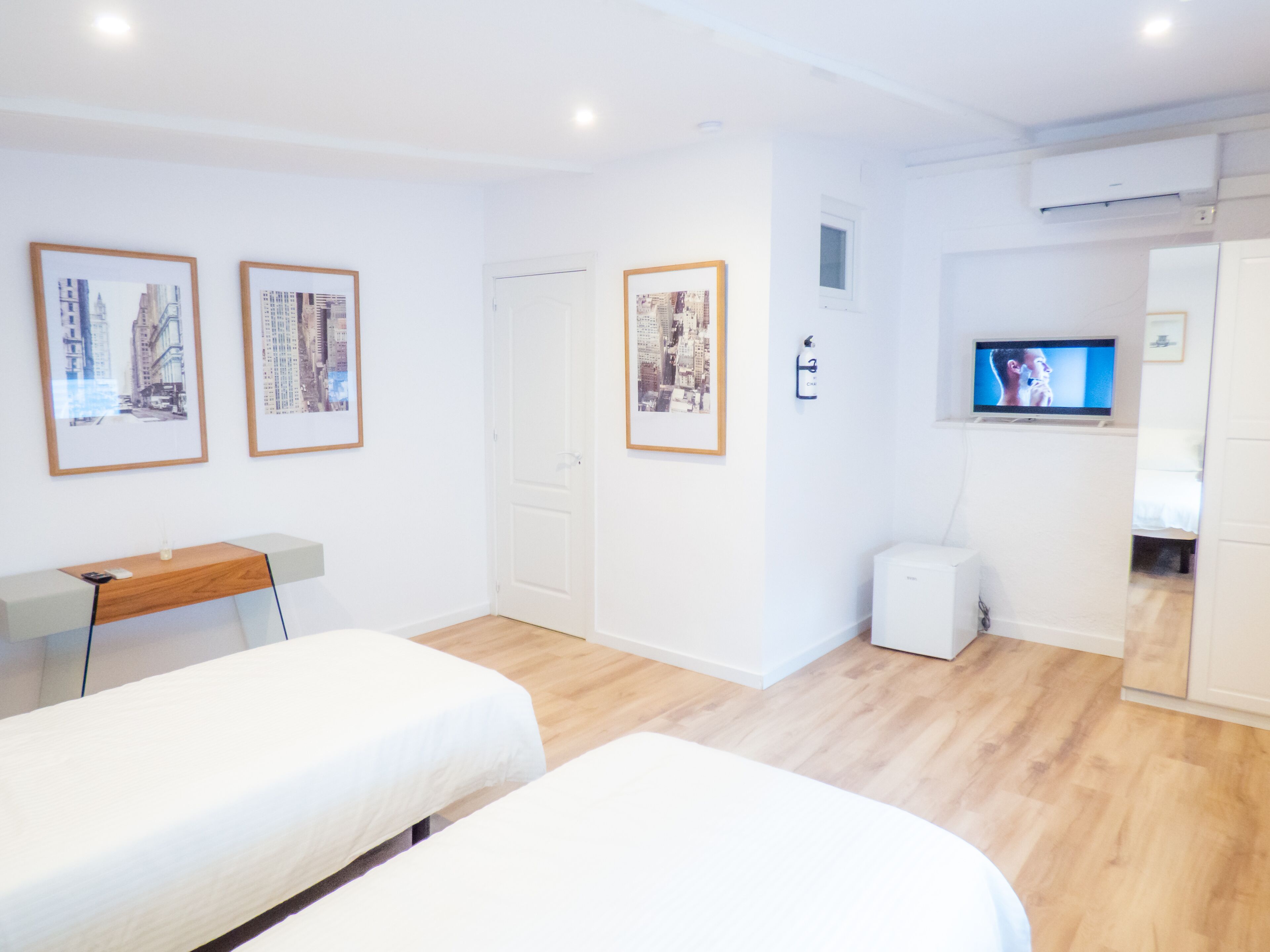 Una habitación moderna y limpia con dos camas, un escritorio y un televisor.