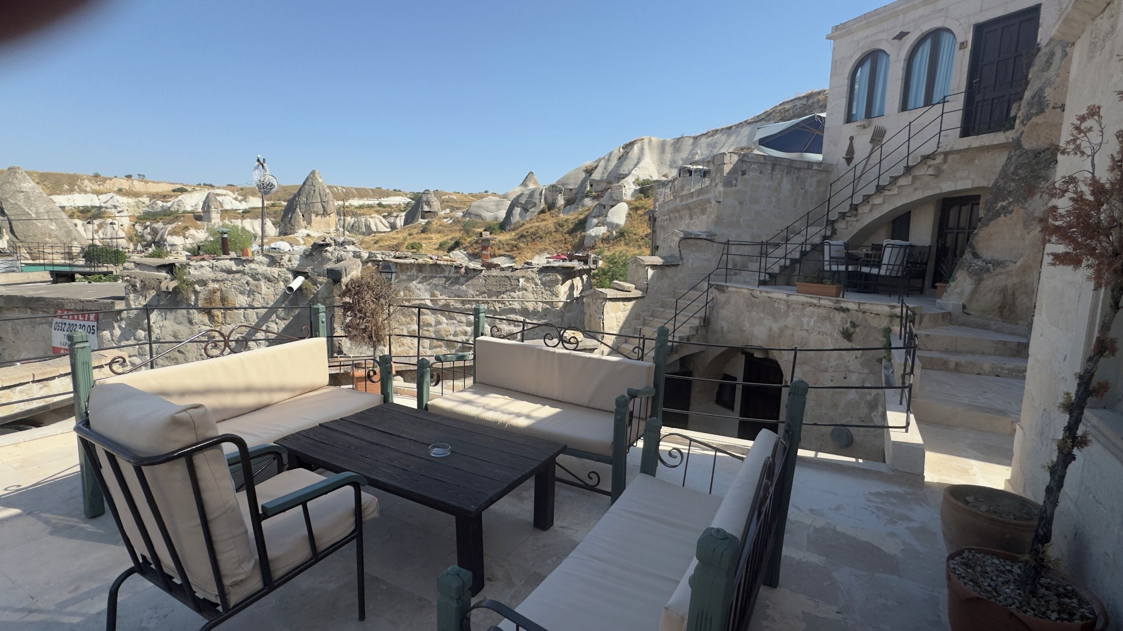 Eine Terrasse mit Außenbestuhlung, einer Steinsäule und Blick auf eine felsige Landschaft.