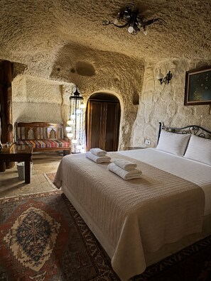 Una habitación con una cama, una silla de madera, un tapete y un techo con textura.
