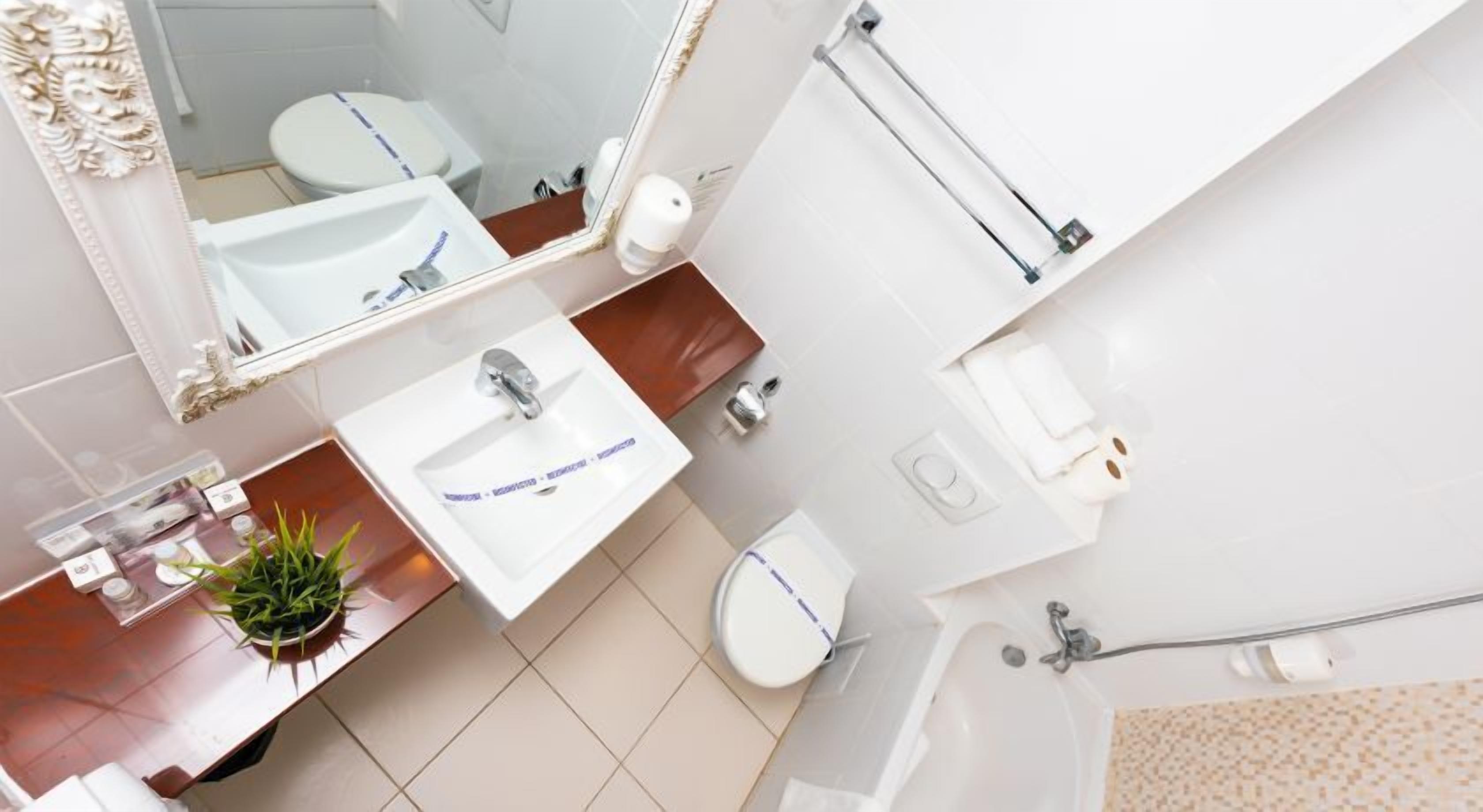 A modern bathroom with a white sink, mirror, toilet, and bathtub.