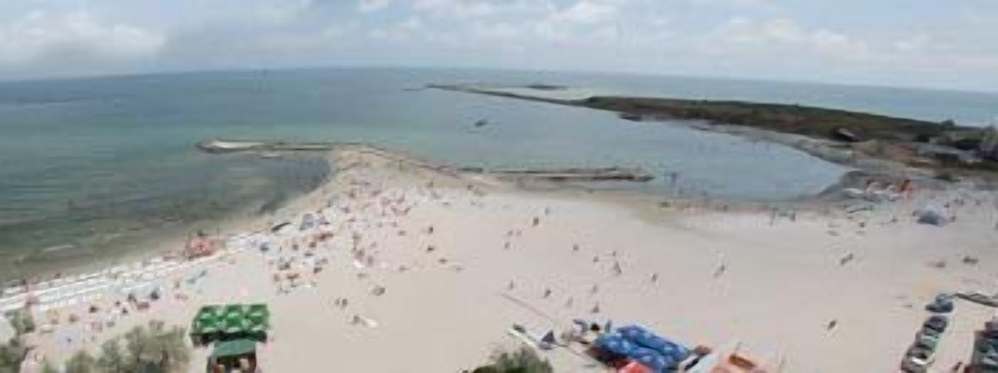 Una playa con arena, algunas sombrillas y unas cuantas personas.