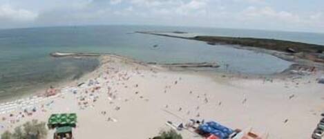 Una playa con arena, algunas sombrillas y unas cuantas personas.