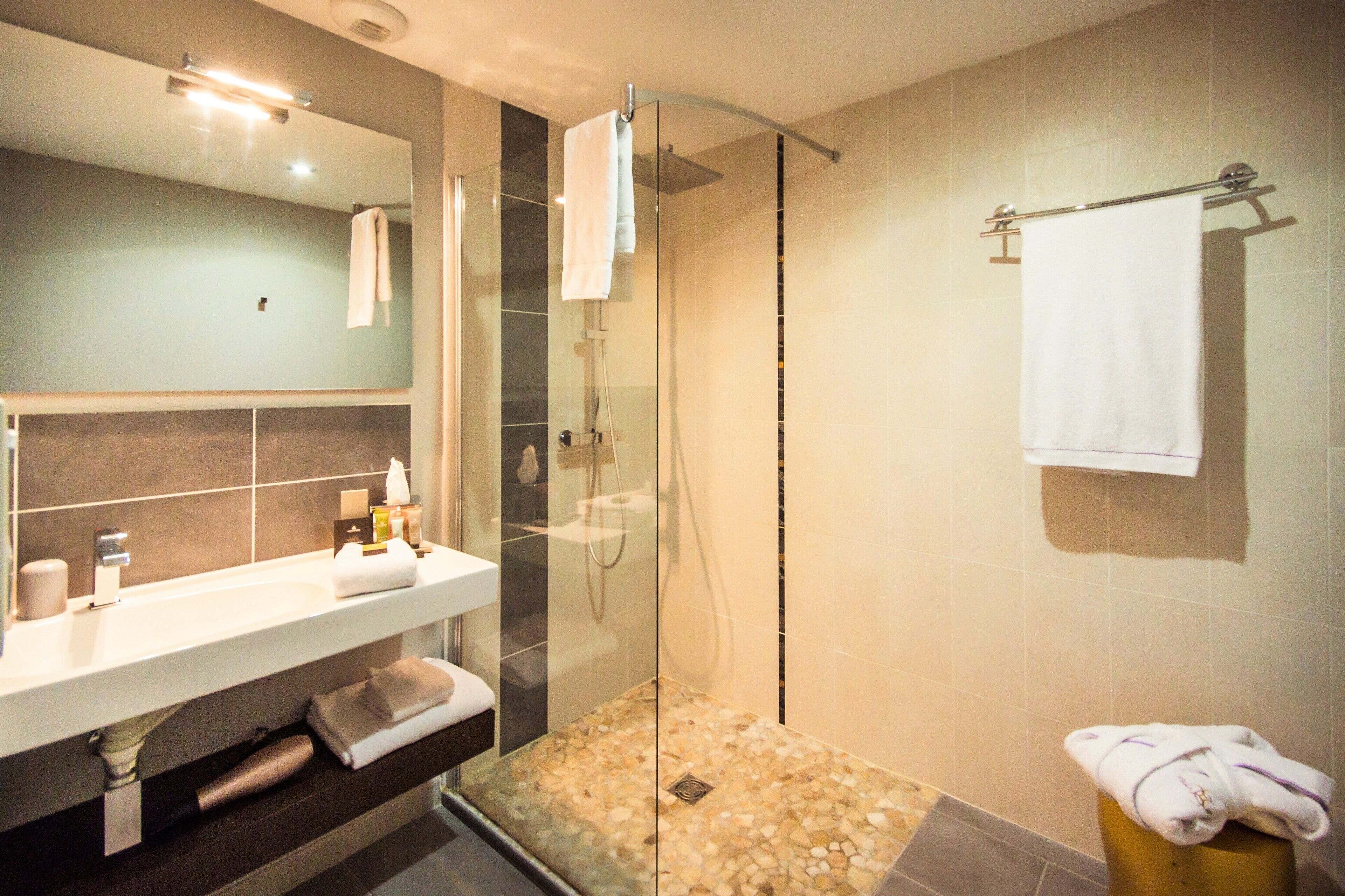 A modern bathroom with a glass-enclosed shower, a white sink, and a towel rack.