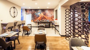 A modern dining area with tables and chairs, a decorative wall mural, and a metal partition.