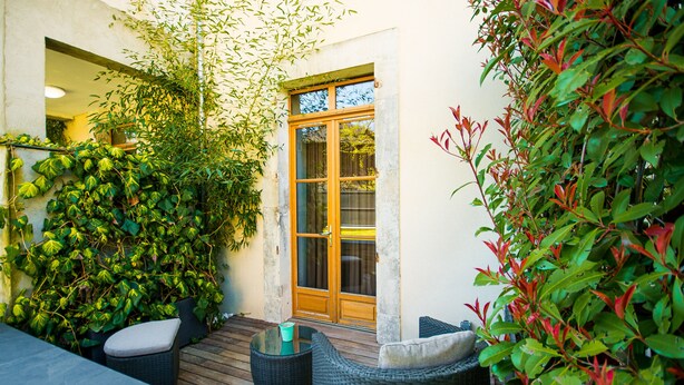 A patio area with wicker furniture, a wooden deck, and a glass door leading to an interior space.