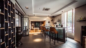 A modern kitchen with a bar area, wooden shelves, and a large window.