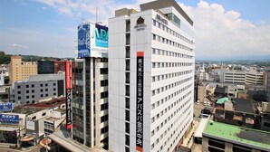 A multi-story building with signage for the APA Hotel and APA Group.