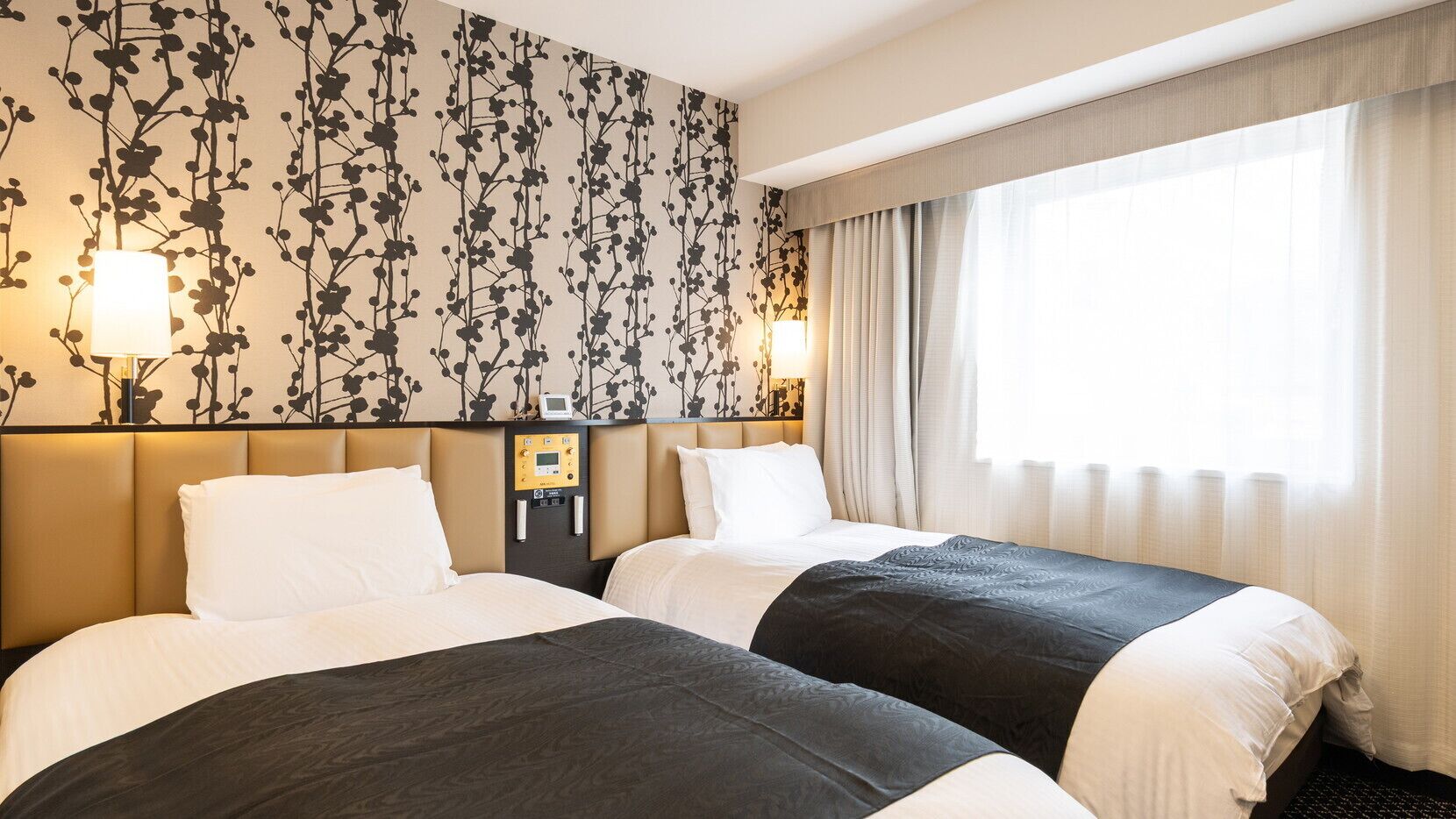 Ein Hotelzimmer mit zwei Betten, einer Steuerung und einem großen Fenster mit Vorhängen.