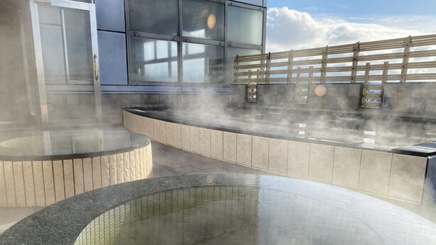 A modern spa area with a large central hot tub surrounded by seating areas and a wooden deck.