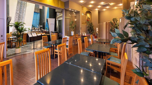 Un restaurante con mesas, sillas, una barra y plantas en macetas.