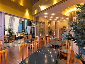 Un restaurante con mesas, sillas, una barra y plantas en macetas.