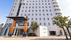 Un hotel de varios pisos con un diseño moderno, que cuenta con una entrada destacada y una estructura naranja distintiva.