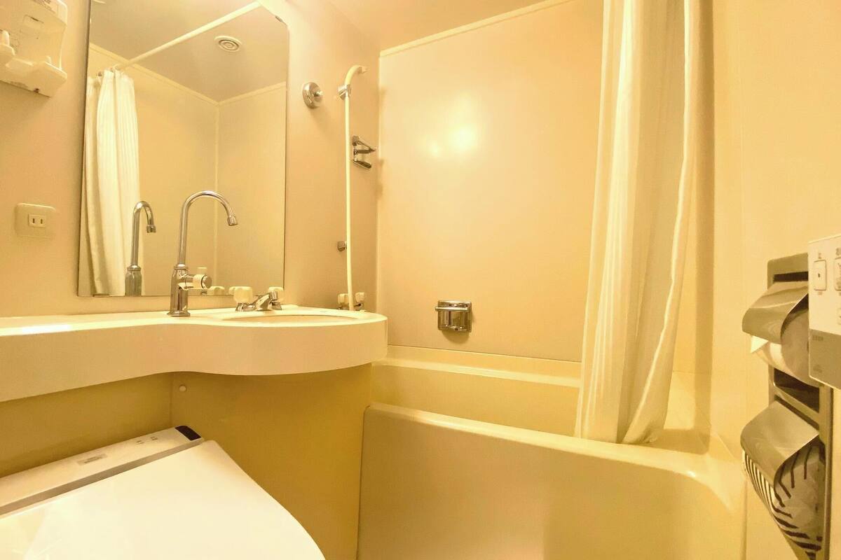 A bathroom with a sink, mirror, shower, and toilet.