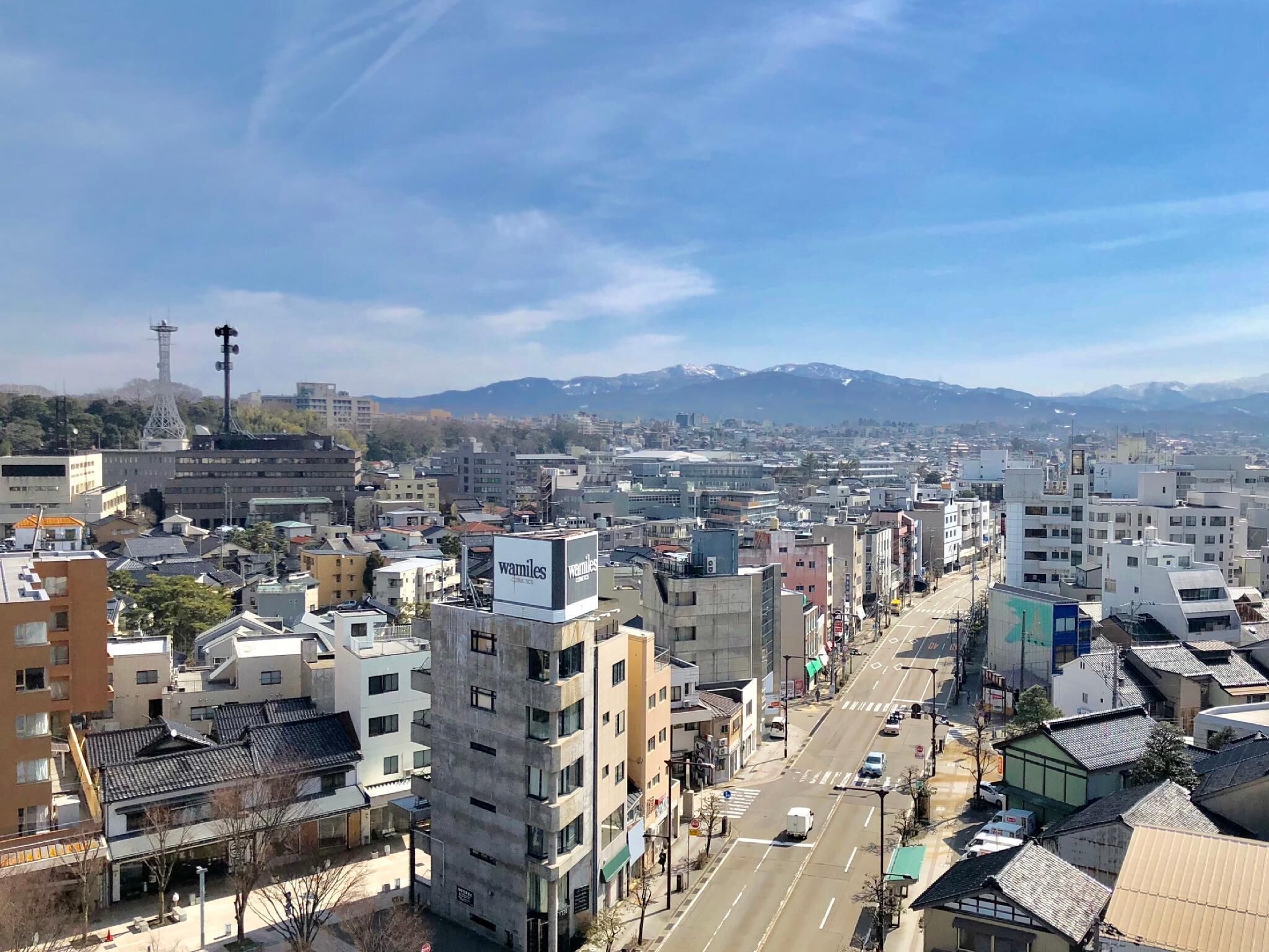 A cityscape with modern and traditional buildings, a clear sky, and distant mountains.