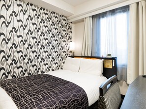 Een hotelkamer met behang met een patroon, een bed met witte lakens, een nachtkastje met een lamp, een bedieningspaneel en een raam met gordijnen.