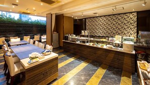Ein moderner Essbereich mit einem Buffet, einem langen Tisch mit Stühlen und einer Wand mit Muster im Hintergrund.