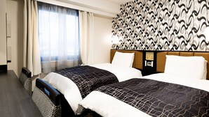 Ein Hotelzimmer mit zwei Betten, einer Wand mit Muster, einem Fenster mit Vorhängen und einer Bedienkonsole an der Wand.