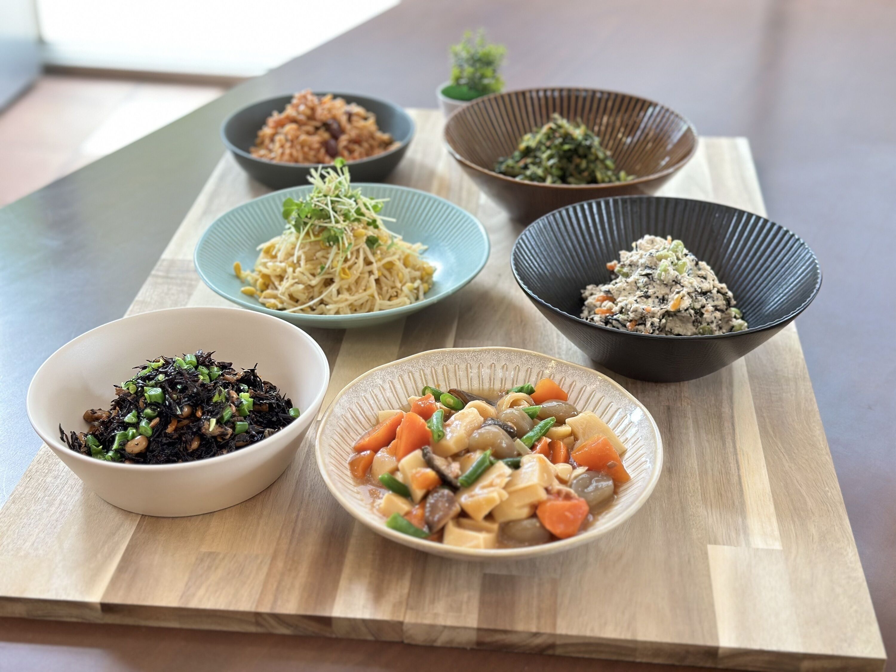 A wooden table with six bowls of various Asian dishes.