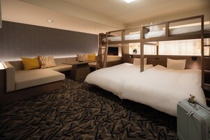 Habitación de hotel con literas, sofá, escritorio y alfombra estampada.