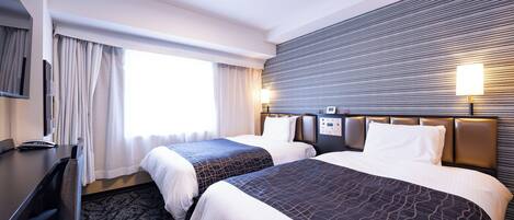 Habitación de hotel con dos camas, un escritorio, una silla, un televisor y una ventana con cortinas.