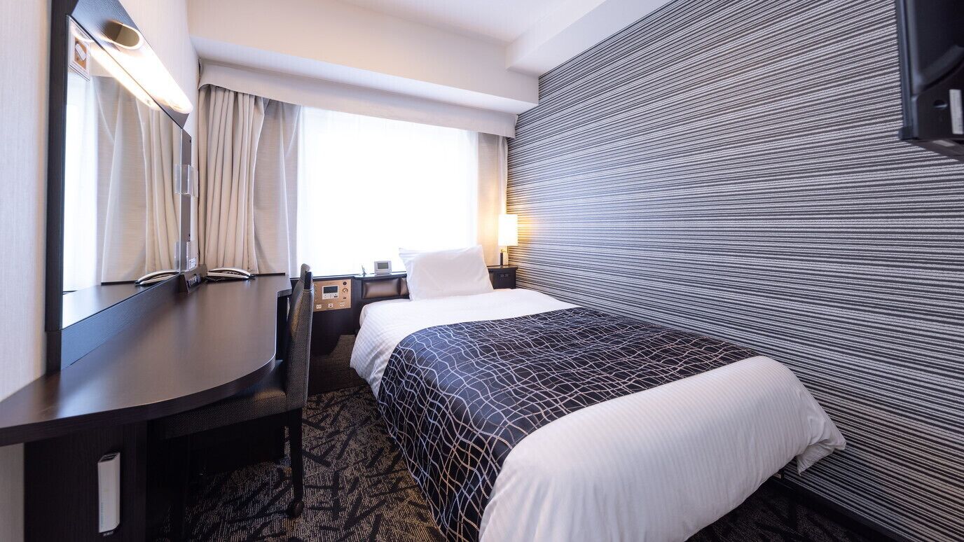 Une chambre d’hôtel équipée d’un lit, d’un bureau, d’une chaise, d’une lampe et d’un téléviseur.